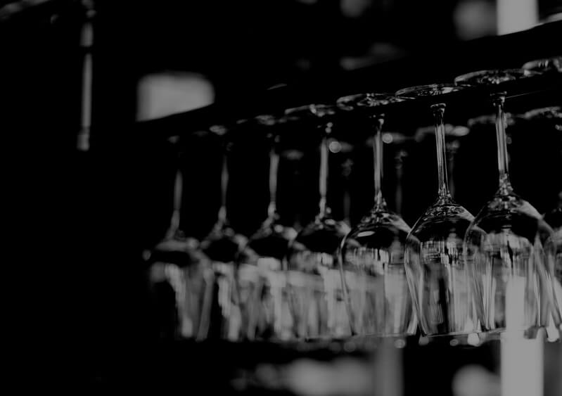 several wine glasses upside down hanging from a support in a bar