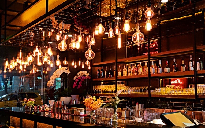 Inside of a bar with multiple yellow lamps turned on